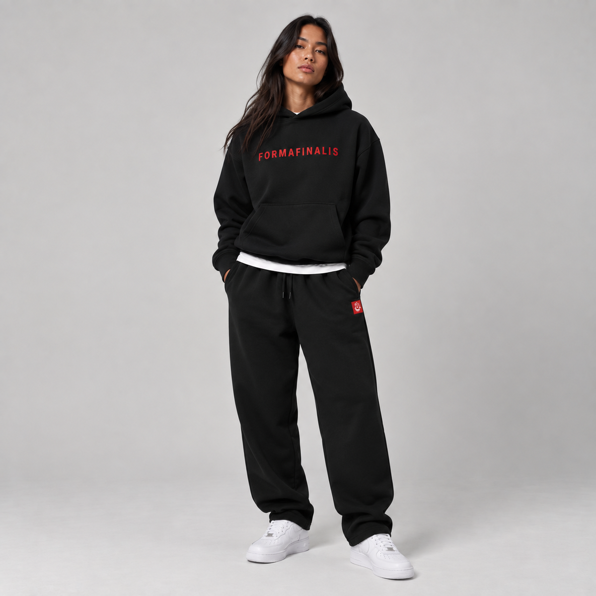 Female Model wearing a black FF Capsule 500 GSM heavyweight cotton hoodie with red embroidered FormaFinalis wordmark and black relaxed cuffless fleece joggers